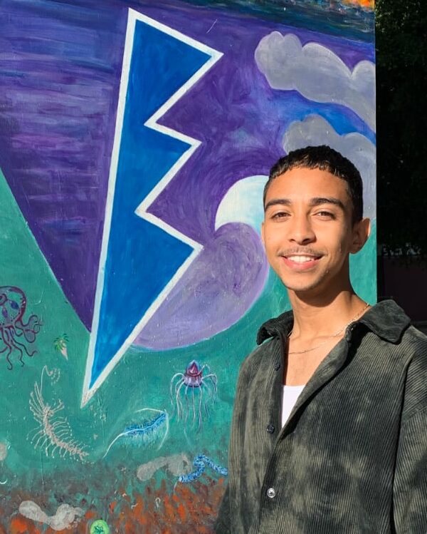 Elijah Catalan standing in front of vaporwave-esque art