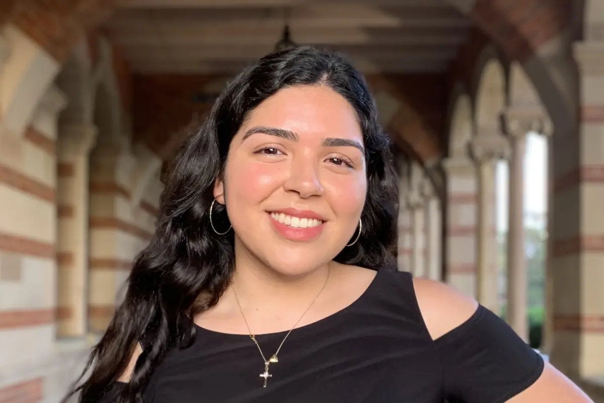 Desiree Felix stands in a brick archway corridor on the UCLA campus.