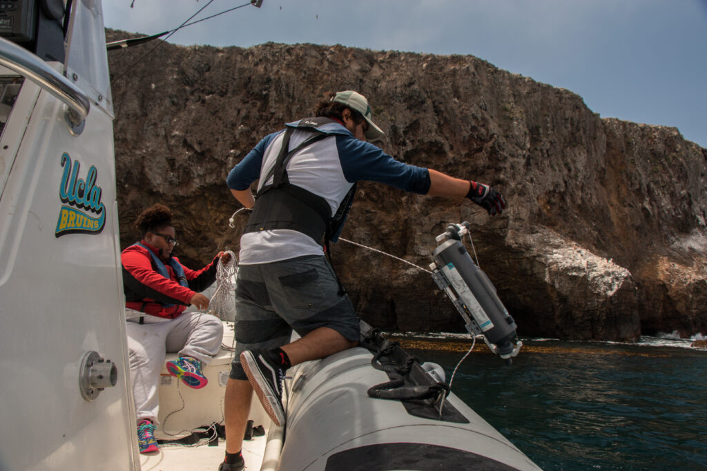 researcher collecting water sample from boat