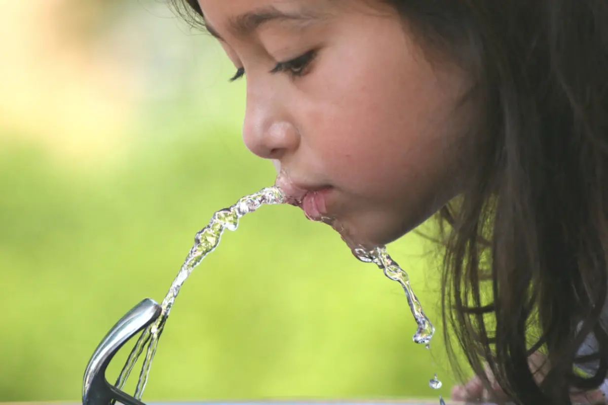 child drinking from water fountain