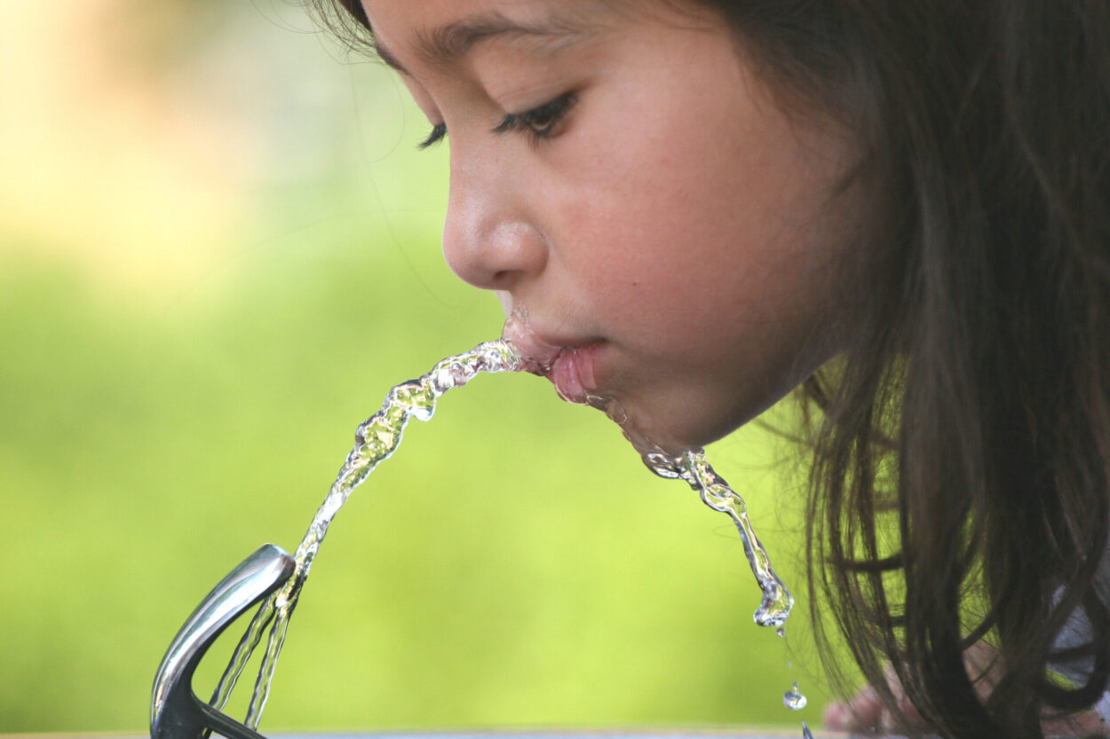 child drinking from water fountain