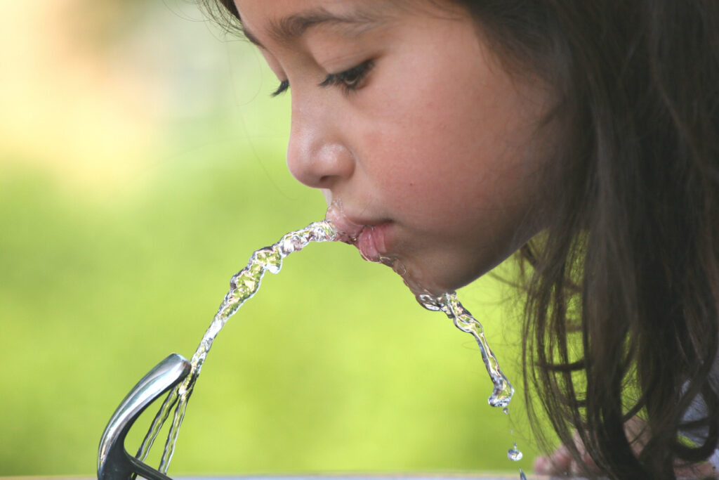 child drinking from water fountain