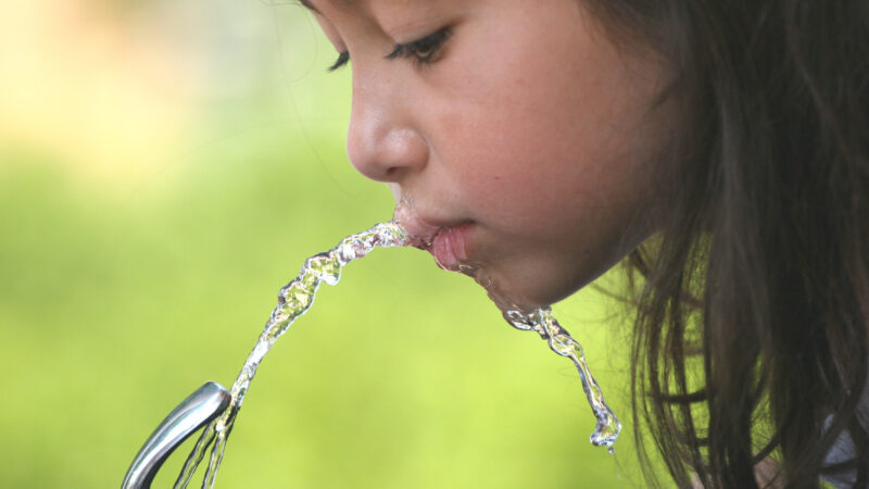 child drinking from water fountain