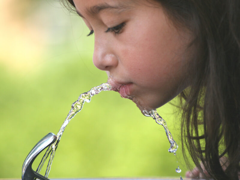 child drinking from water fountain