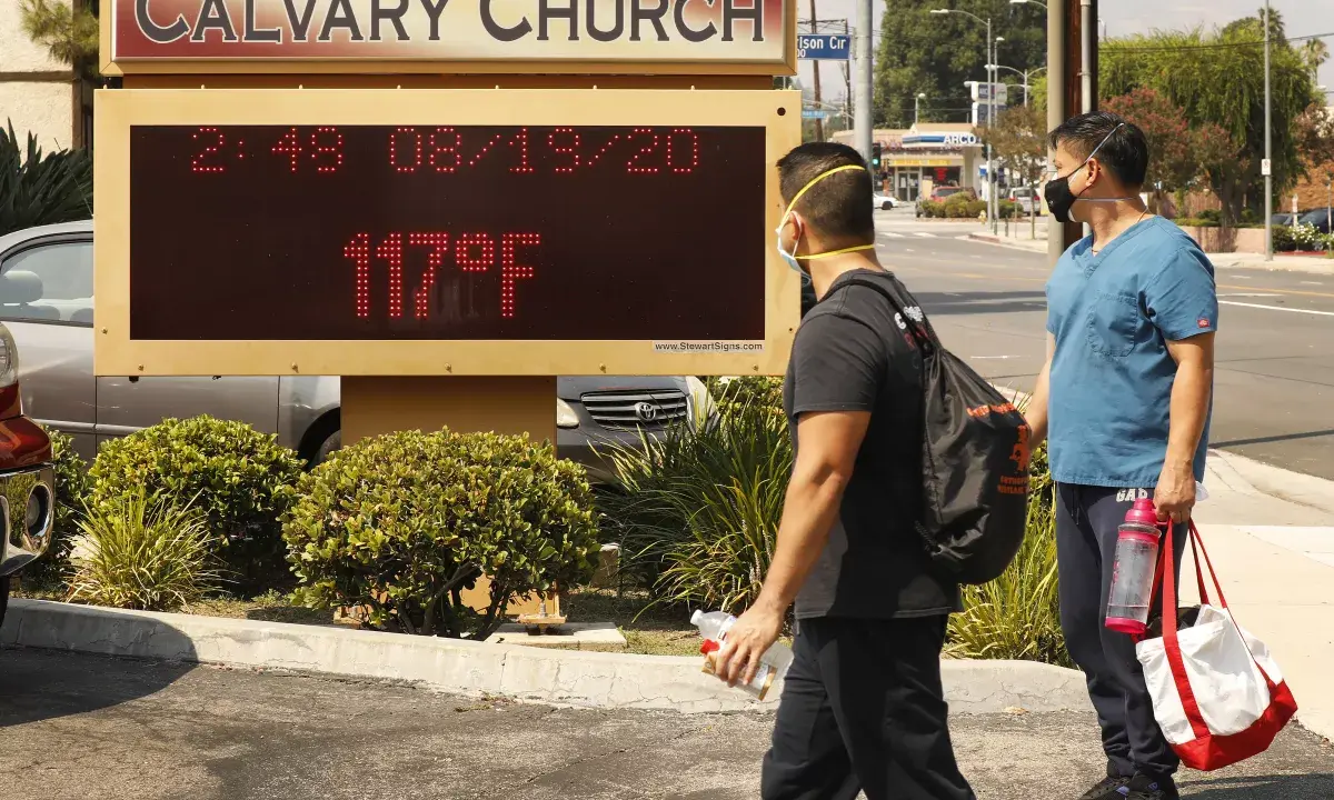 Two people in front of the Calvary Church display board in Woodland Hills. The board displays a temperature of 117 degrees Fahrenheit on August 19, 2020.