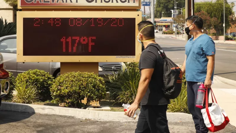 Two people in front of the Calvary Church display board in Woodland Hills. The board displays a temperature of 117 degrees Fahrenheit on August 19, 2020.