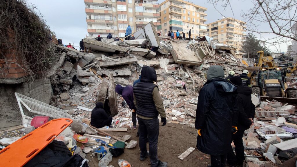 People looking at collapsed buildings in Turkey after the February 2023 earthquake