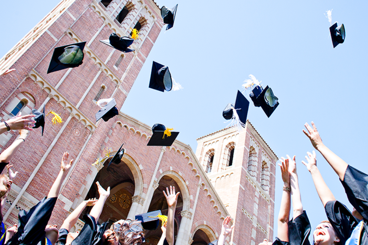 UCLA graduates toss their caps in the air in front of Royce Hall