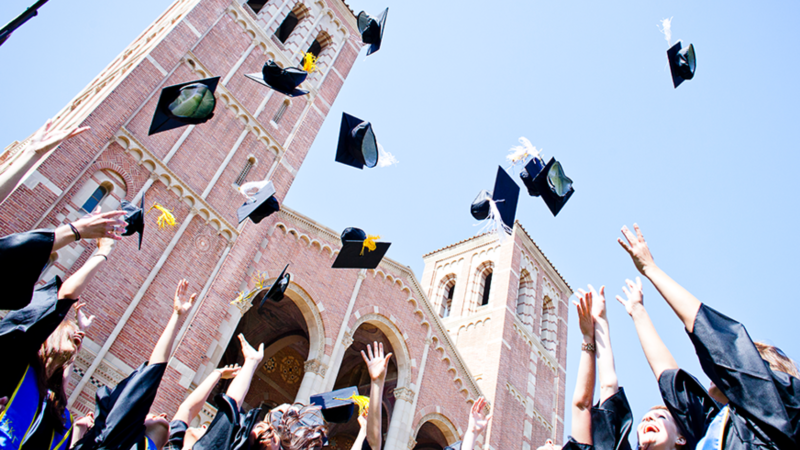 UCLA graduates toss their caps in the air in front of Royce Hall