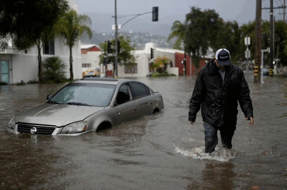 A man walks past a submerged vehicle on a flooded street- Thursday- Dec - - in Santa Barbara- Calif Jae C Hong : AP