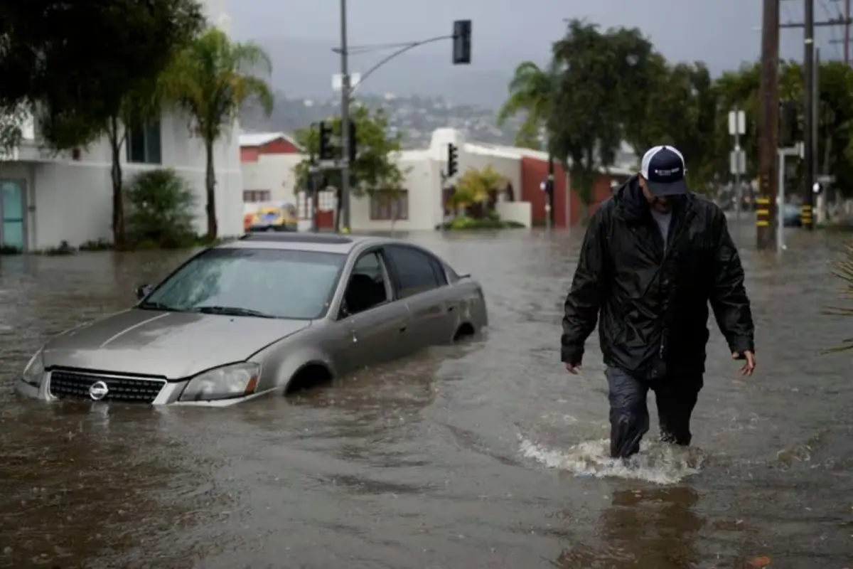 A man walks past a submerged vehicle on a flooded street- Thursday- Dec - - in Santa Barbara- Calif Jae C Hong : AP
