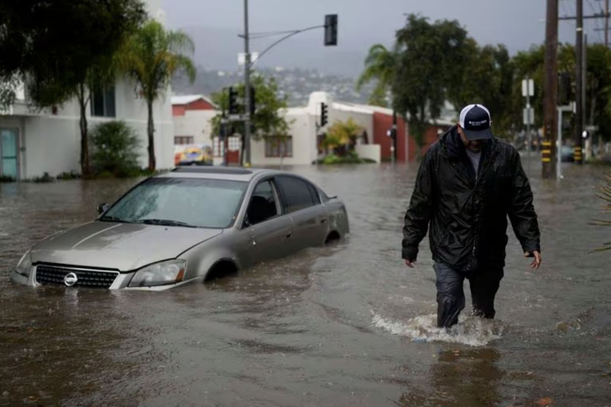 A man walks past a submerged vehicle on a flooded street- Thursday- Dec - - in Santa Barbara- Calif Jae C Hong : AP