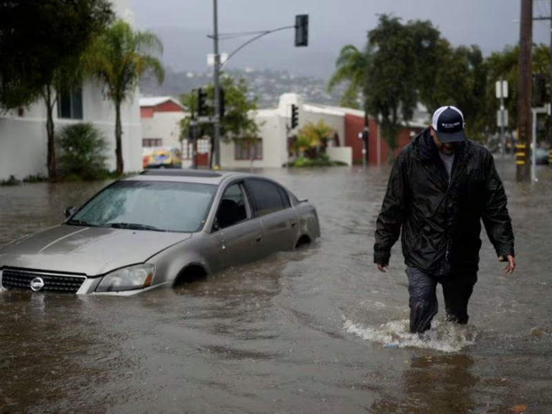 A man walks past a submerged vehicle on a flooded street- Thursday- Dec - - in Santa Barbara- Calif Jae C Hong : AP