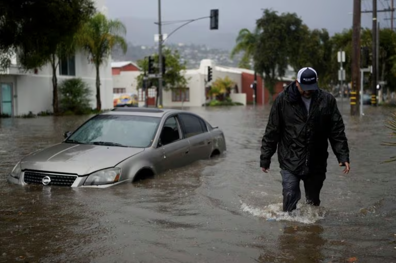 A man walks past a submerged vehicle on a flooded street- Thursday- Dec - - in Santa Barbara- Calif Jae C Hong : AP