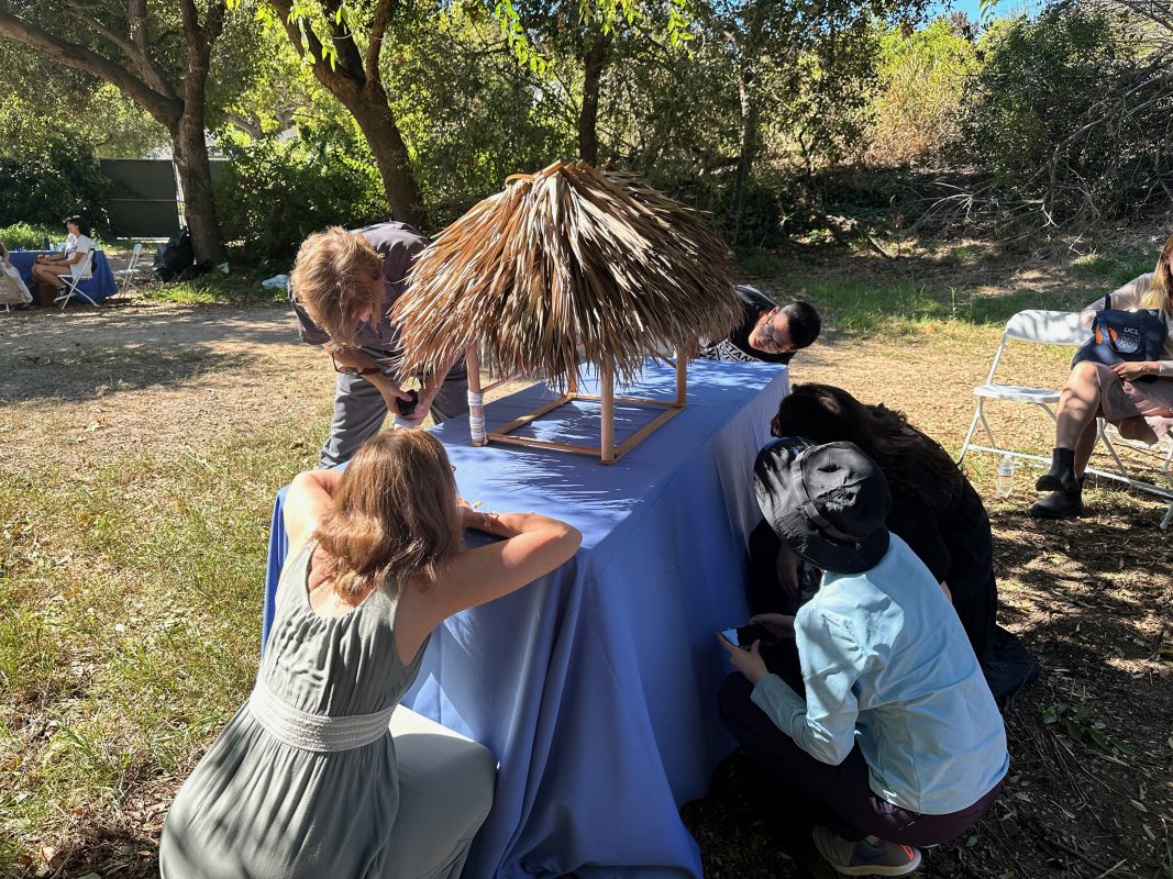 People examine architectural model of a seminole chickee