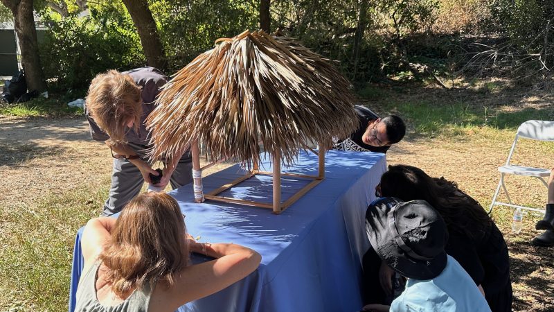 People examine architectural model of a Seminole chickee building