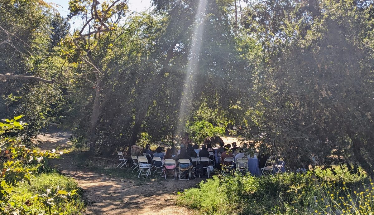 Attendees seated on folding chairs facing visiting speaker outdoors at Sage Hill.