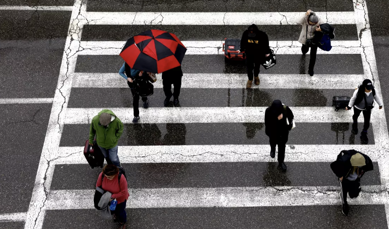 Travelers arrive at LAX in the rain last week. Another wet weather pattern is headed toward California, with rainfall expected through early next week. (Christina House / Los Angeles Times)