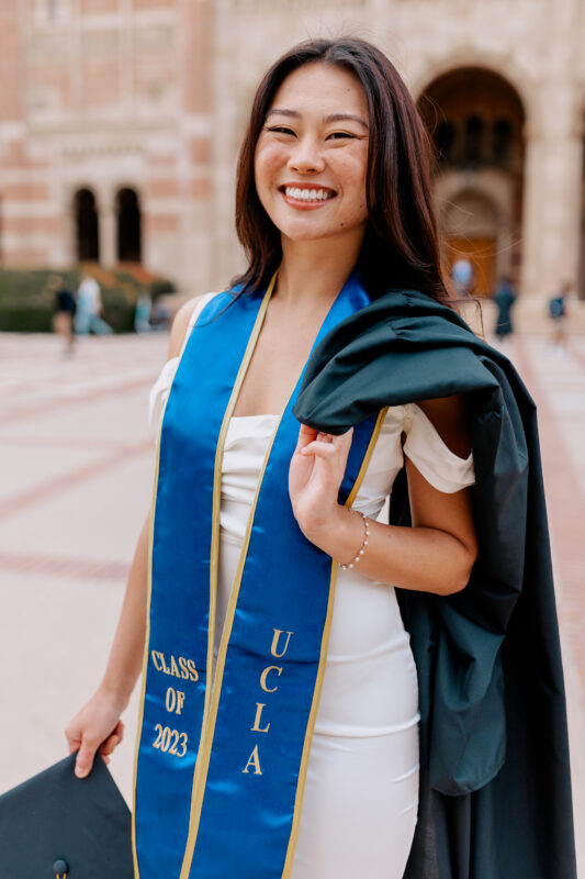 Sonobe holding her graduation cap and gown in UCLA’s Dickson Plaza