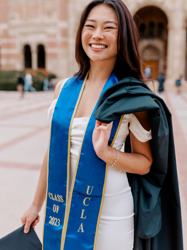 Sonobe holding her graduation cap and gown in UCLA’s Dickson Plaza