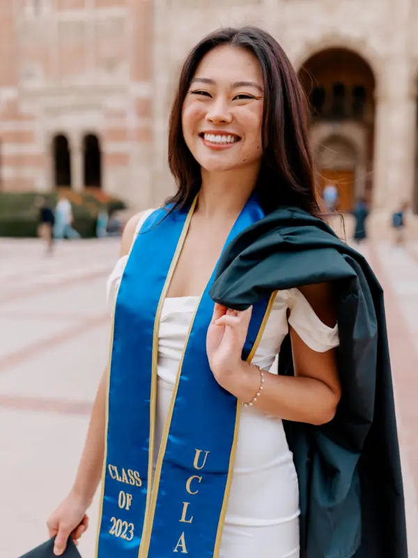 Sonobe holding her graduation cap and gown in UCLA’s Dickson Plaza