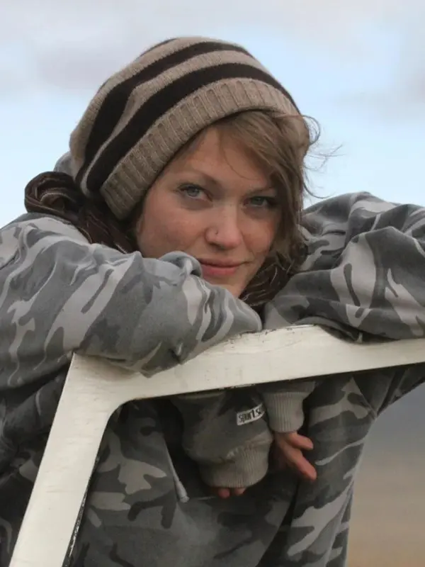 Ali Swanson leaning on a metal frame outdoors at a field site