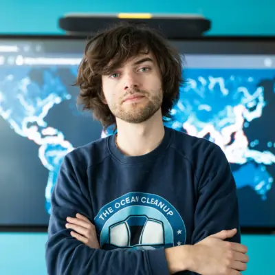 Boyan Slat standing in front of a screen displaying a world map of ocean data