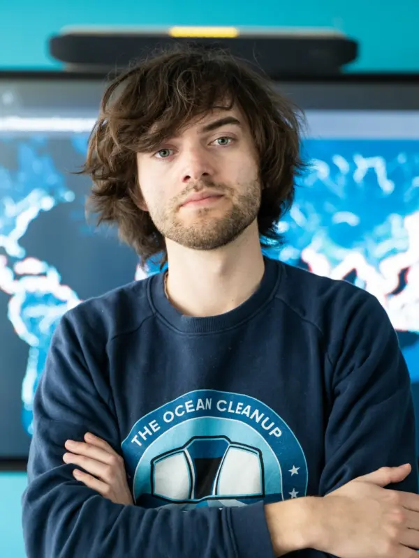 Boyan Slat standing in front of a screen displaying a world map of ocean data