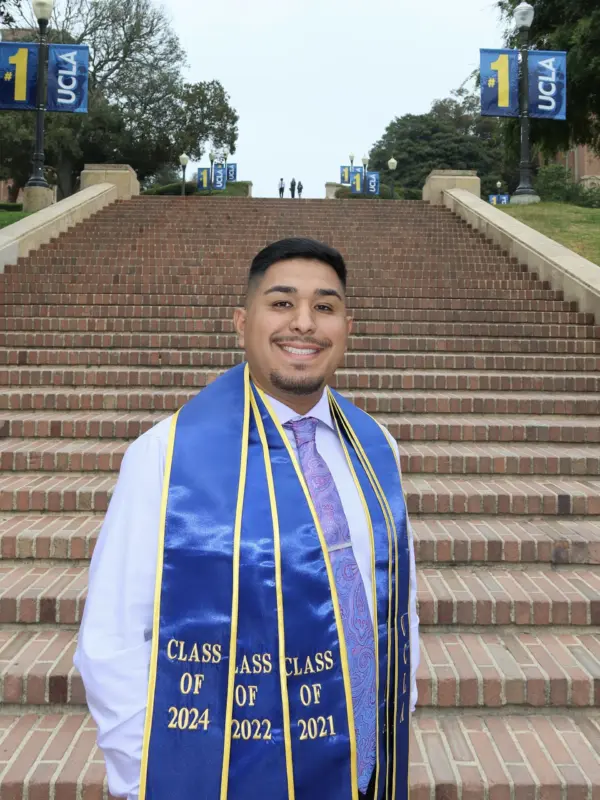 Marcos R. Magaña on the Janss Steps at UCLA, wearing graduation stoles.