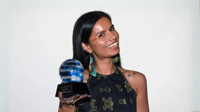 Nina Gualinga holds her glass Pritzker Award trophy at the 2024 award ceremony.