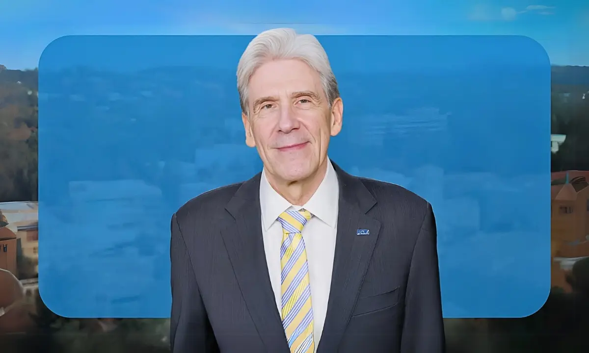 UCLA Chancellor Julio Frenk in a video message, with a blurred campus view behind him.