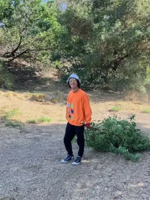 Juana D. H. Alatorre standing on a dirt trail beside cleared brush in an oak woodland field site.