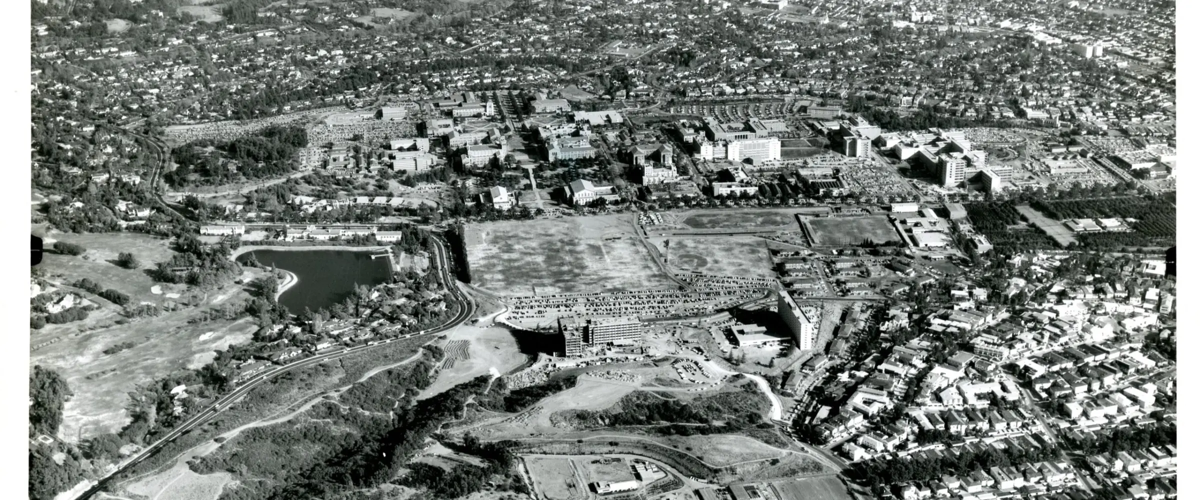 Historic aerial view of the UCLA campus around 1959, surrounded by neighborhoods, with an undeveloped vegetated area at lower left.