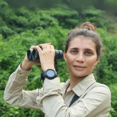 Seema Lokhandwala holding binoculars at a green field site