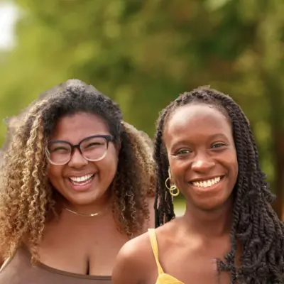 Maya Smith and Joye Williams outdoors among trees.