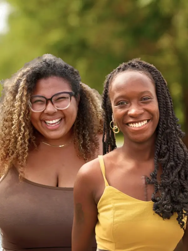 Maya Smith and Joye Williams outdoors among trees.