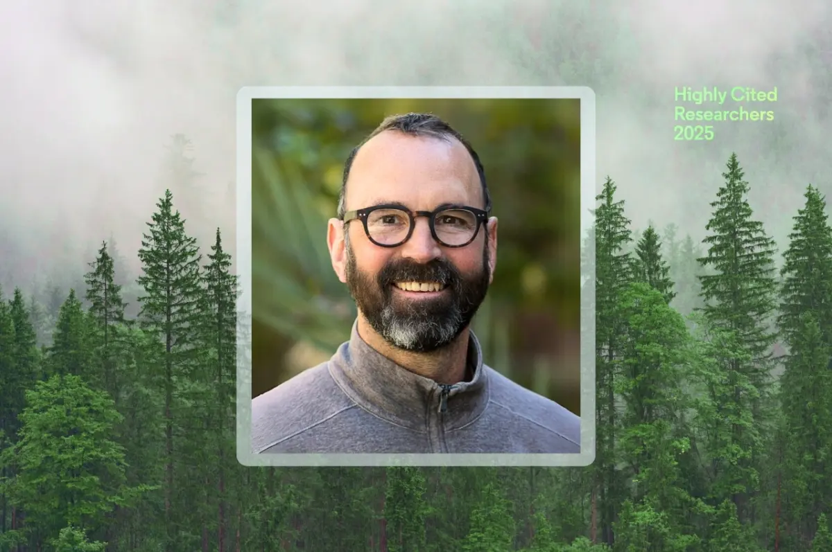 Alex Hall smiles wearing glasses and a gray jacket, centered in a framed headshot over a forest background. Green text in the top right corner reads “Highly Cited Researchers 2025.”