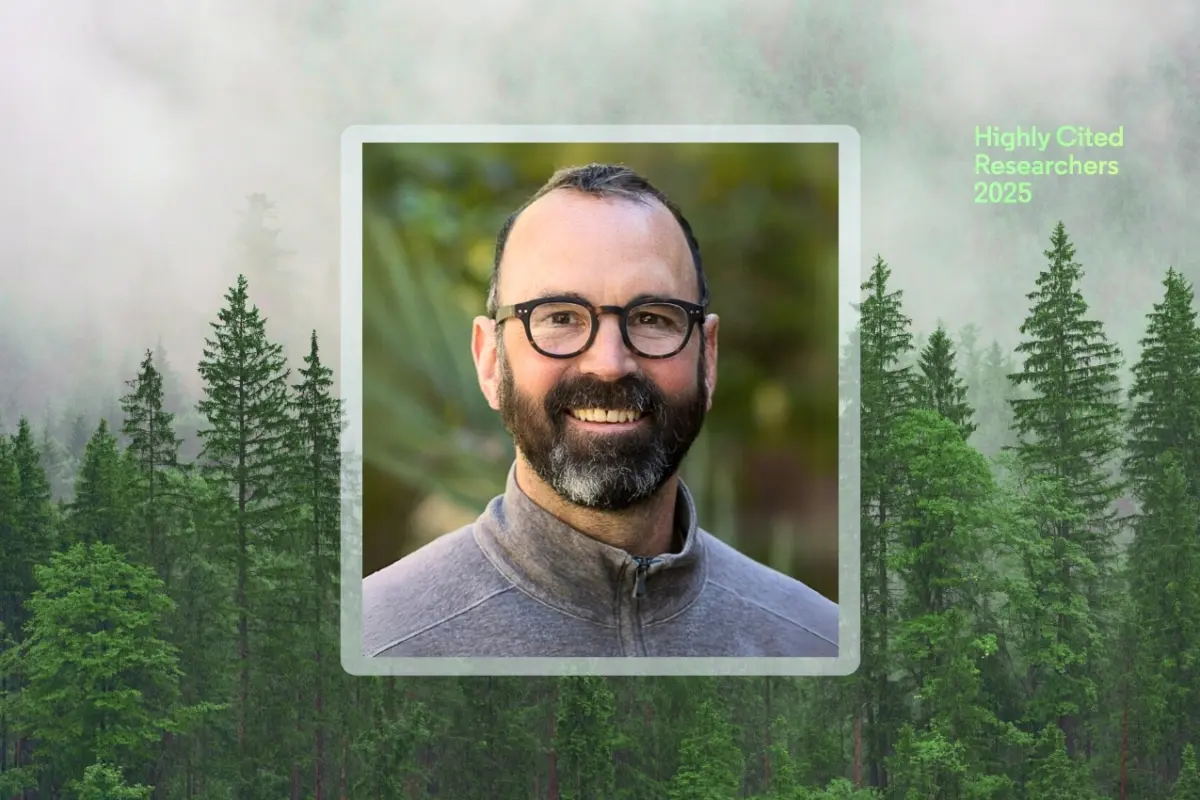 Alex Hall smiles wearing glasses and a gray jacket, centered in a framed headshot over a forest background. Green text in the top right corner reads “Highly Cited Researchers 2025.”