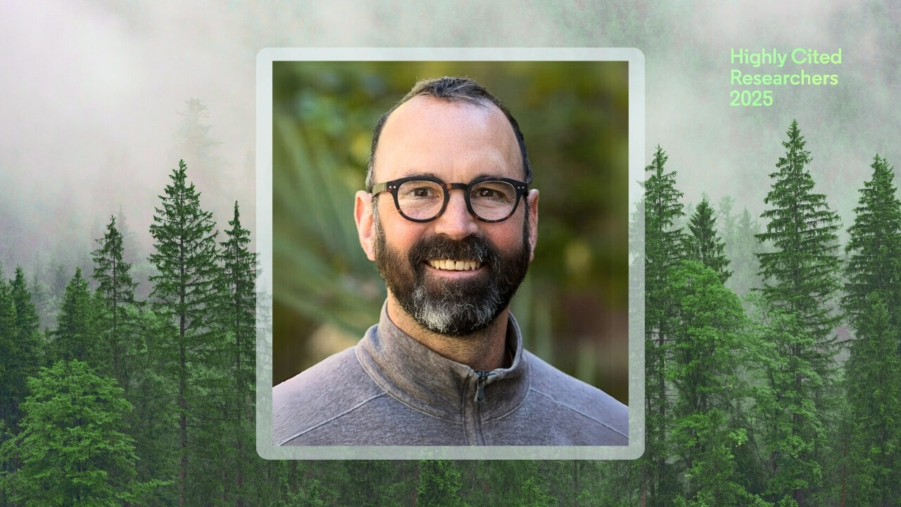 Alex Hall smiles wearing glasses and a gray jacket, centered in a framed headshot over a forest background. Green text in the top right corner reads “Highly Cited Researchers 2025.”