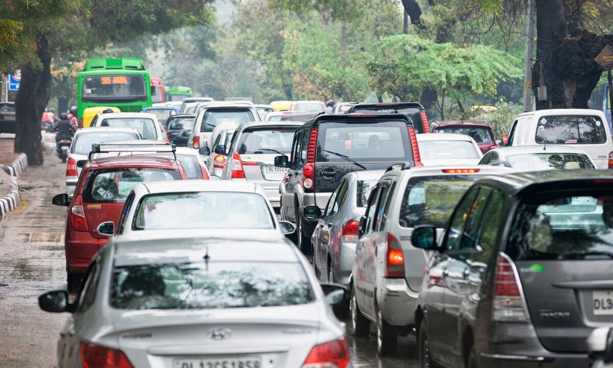 Heavy traffic in Delhi, India showing a mix of cars, SUVs and buses on a crowded urban road.