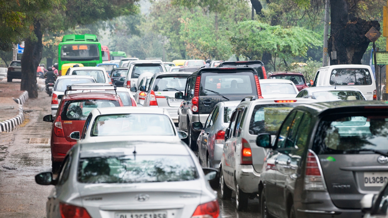 Heavy traffic in Delhi, India showing a mix of cars, SUVs and buses on a crowded urban road.