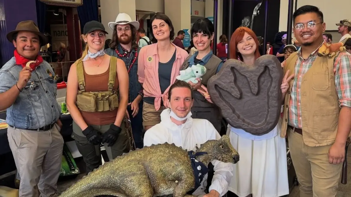 Cosplay for Science group poses with a life-size dinosaur model and a giant footprint cast at the Fleet Science Center.