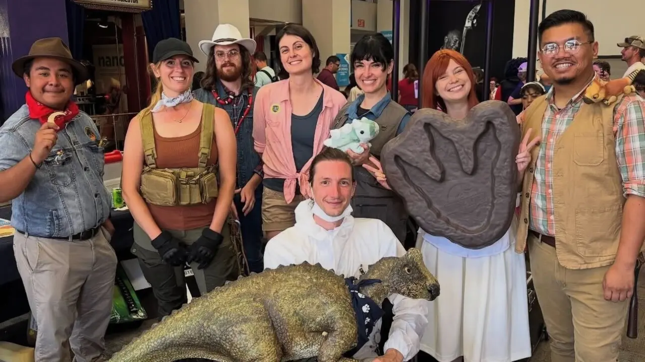 Cosplay for Science group poses with a life-size dinosaur model and a giant footprint cast at the Fleet Science Center.