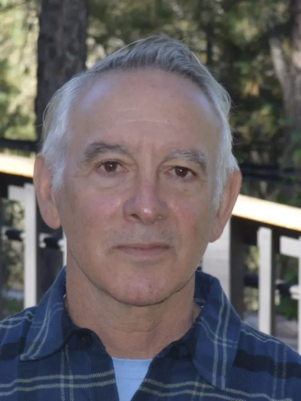 Bill Resnick outdoors on a railed deck among trees