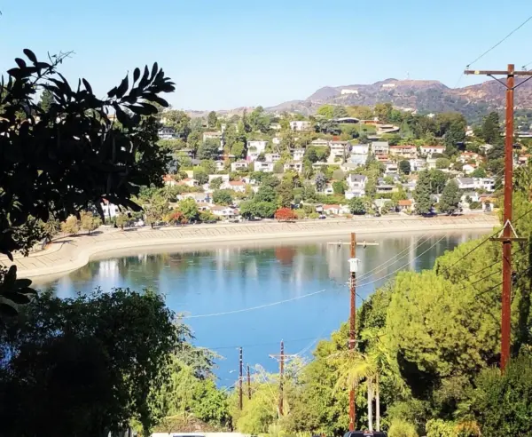 Silver Lake Reservoir ringed by hillside homes, with Griffith Observatory and the Hollywood Sign in the distance.