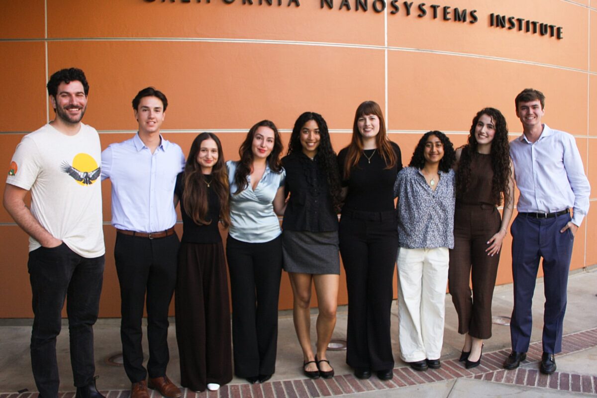 A group of students stands together outside the California NanoSystems Institute building at UCLA.