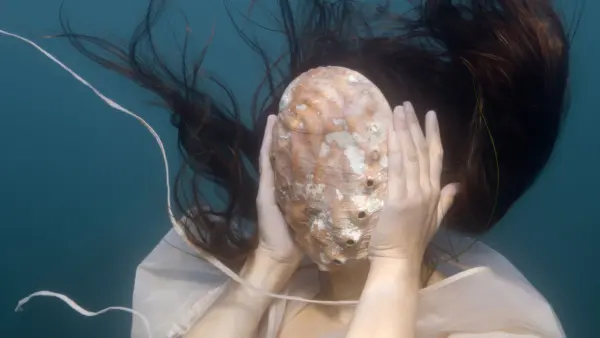 Woman underwater with shell covering her face