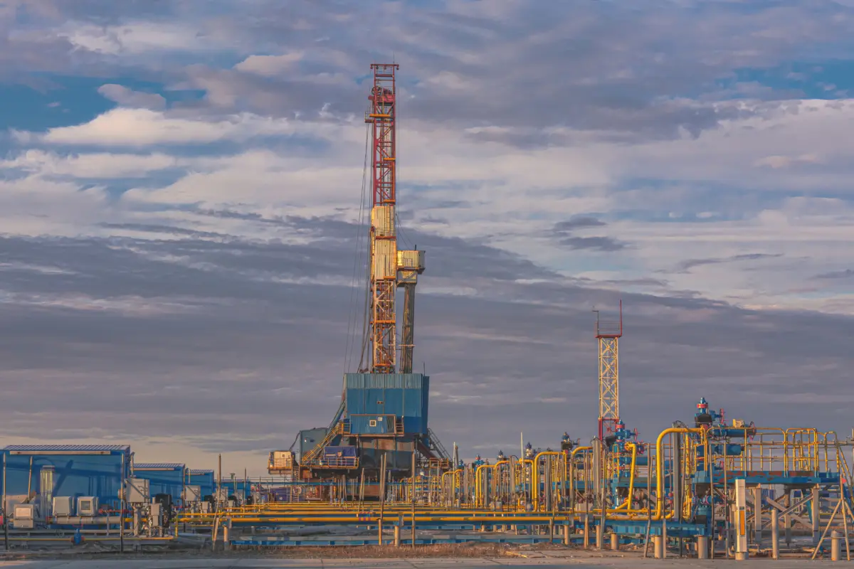 Wells producing natural gas at a field in the Arctic. Fountain equipment and technological strapping of a group of wells for gas production. Drilling rig in the background. Beautiful sky