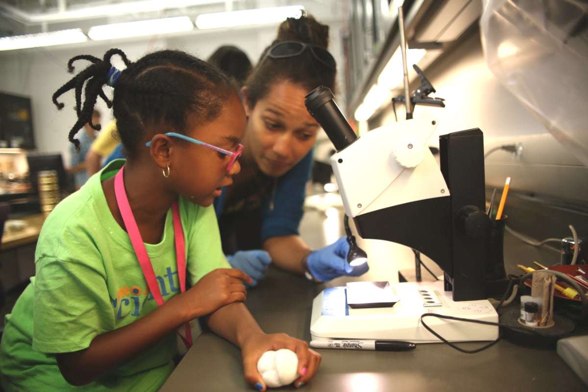 Young student with microscope in lab